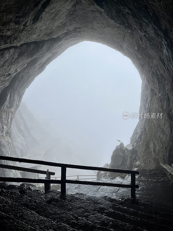 Exit from the cave. Exit from the cave in the fog. A rounded passage into the cave. A hole in the cave. The entrance to the cave.